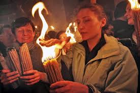 woman holder her hand over candles burning with the Holy Fire